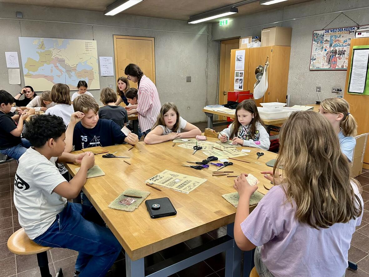 Kinder arbeiten an Bastelprojekten in einem kreativen Workshop, umgeben von Materialien und Sammlungsunterlagen.