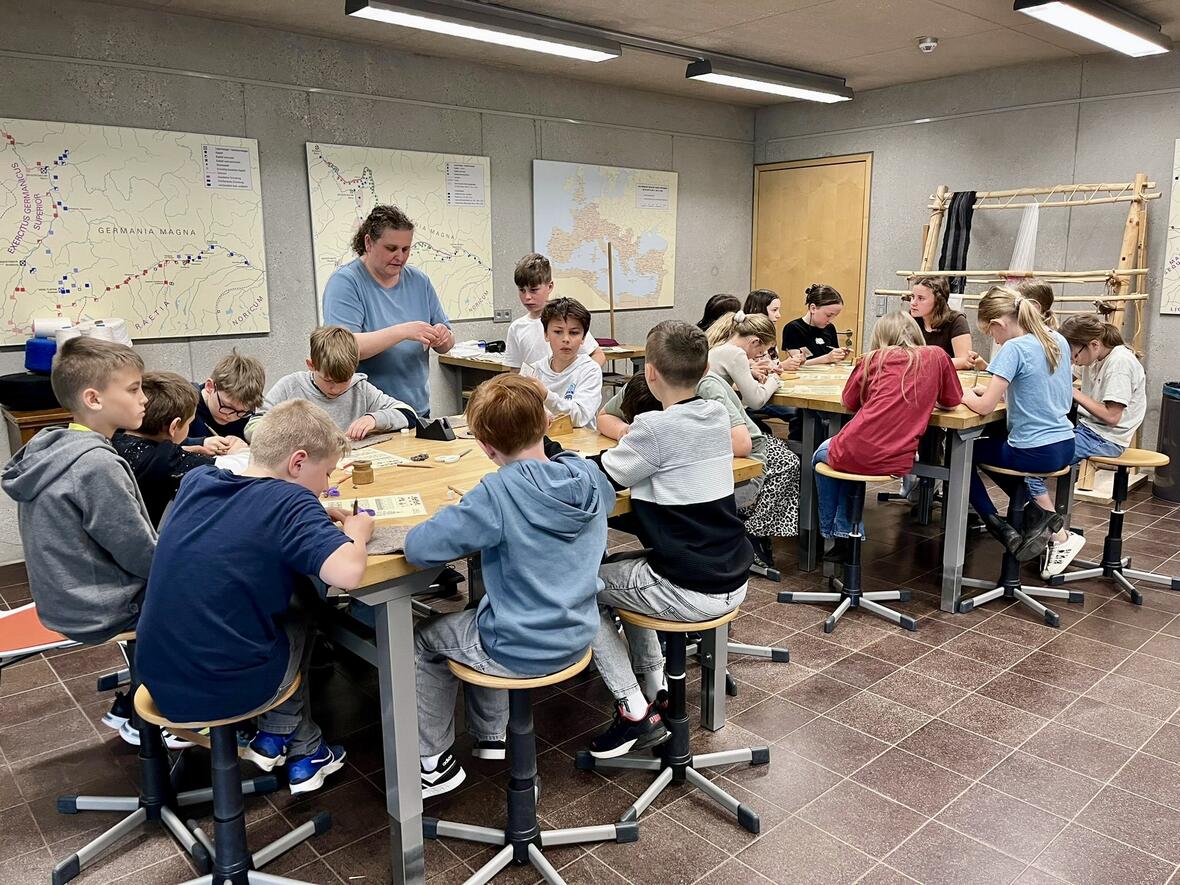 Gruppe von Kindern und einer Betreuerin bei einem Kreativworkshop in einem Schulungsraum.