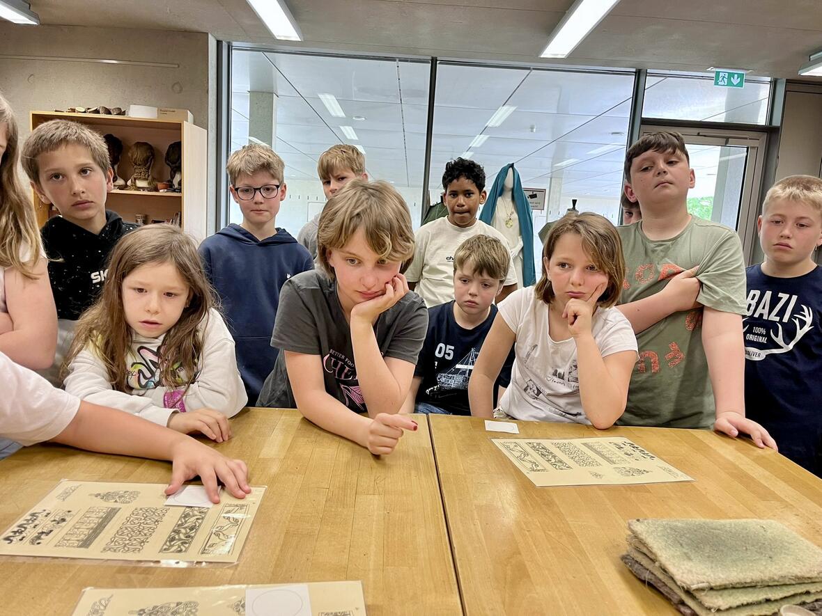Gruppe von Kindern zeigt Interesse an Materialien am Tisch in einem Klassenzimmer.