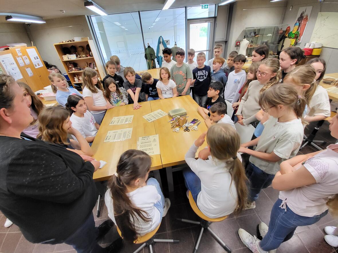 Schülerinnen und Schüler versammeln sich um einen Tisch in einer Lernumgebung, um Anleitungen zu studieren.