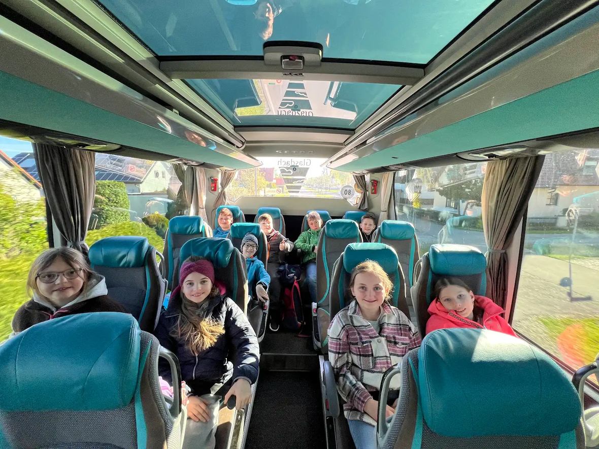 Kinder und Jugendliche sitzen im Reisebus, bereit für einen Ausflug.